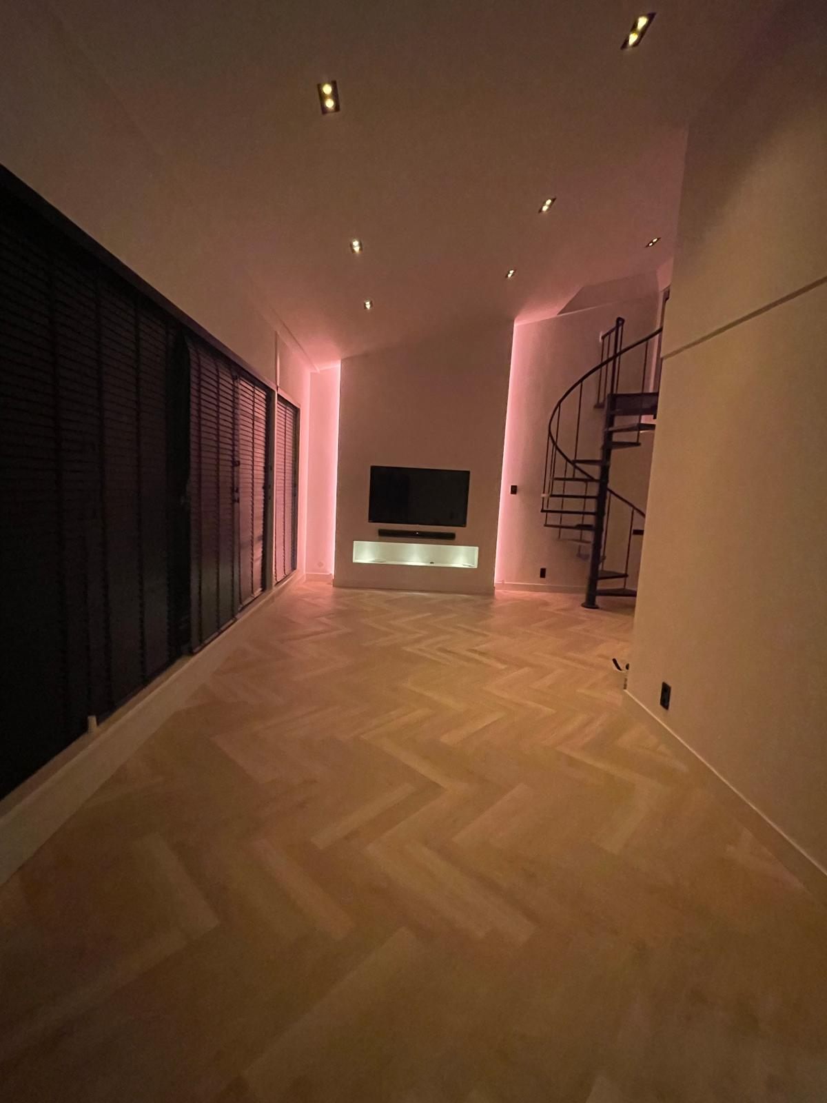 Verbouwde woonkamer met visgraatvloer, sfeerverlichting en wenteltrap